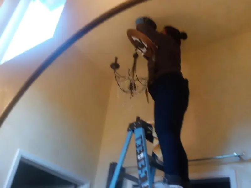 Electrician installing a chandelier in a Alondra Park residence